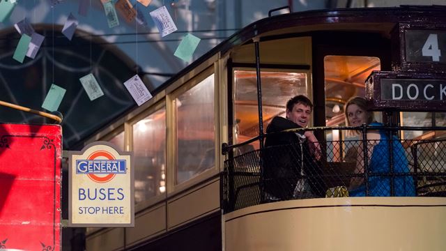 A photo of a man and a woman sitting on the top deck of a tram.