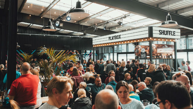 A photo of a crowd of people in a building with a lit up sign in the background.