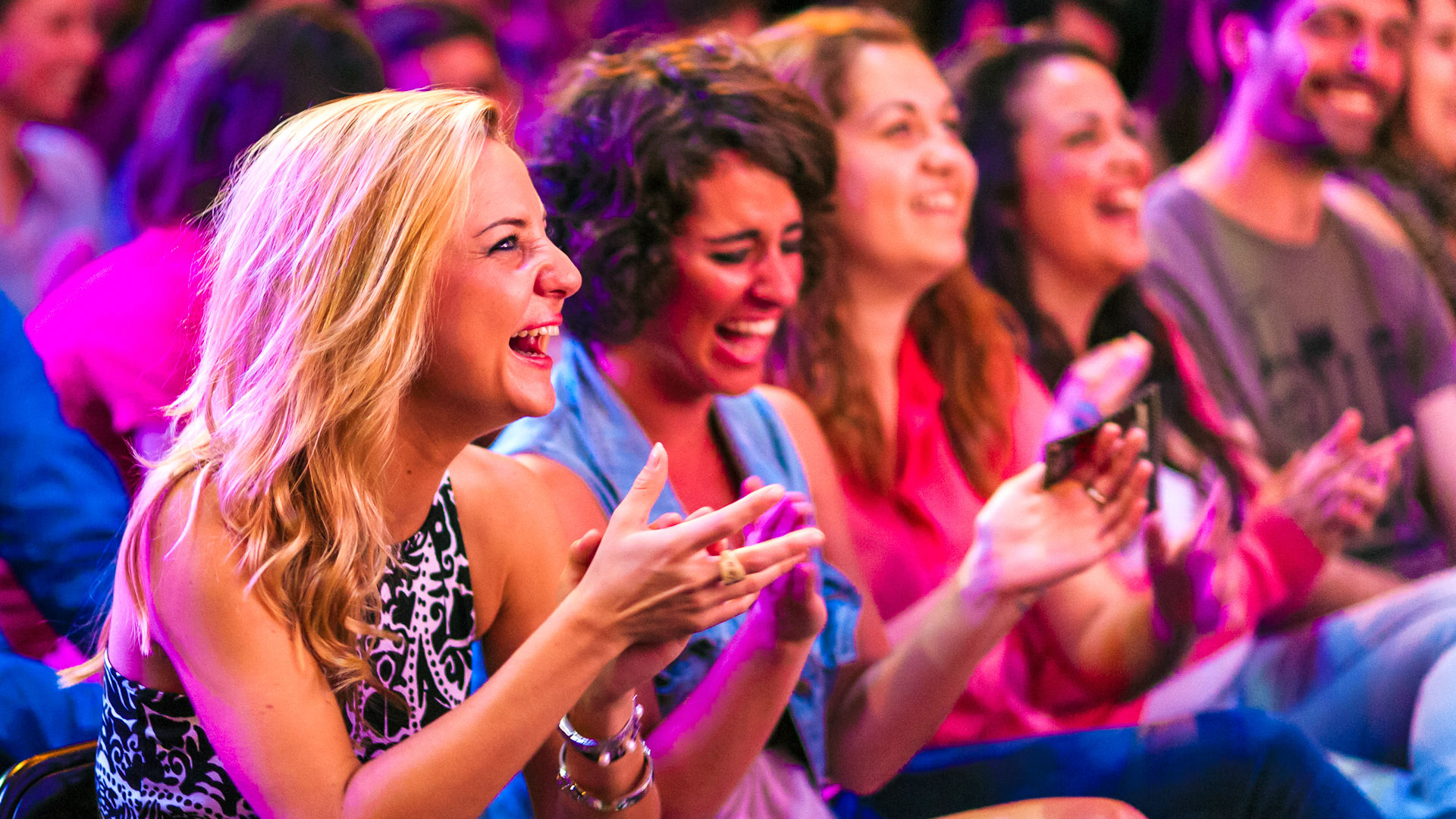 Ladies laughing and clapping at the Comedy Carnival in Leicester Square.