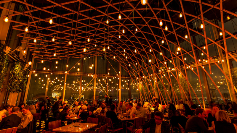 Enjoy sweeping views from the terrace and floor-to-ceiling windows at Sushisamba. Credit: Sushisamba. Image courtesy of Sushisamba. The interior of Sushisamba by evening, people enjoying themselves.