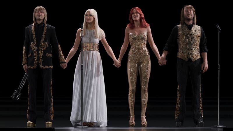 Digital avaatrs of the four group members of ABBA holding hands on stage, as if taking applause during a curtain call.