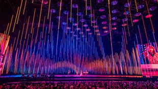 ABBA Arena stage lit up in pink, orange and purple lights during a live performance of ABBA Voyage in London.