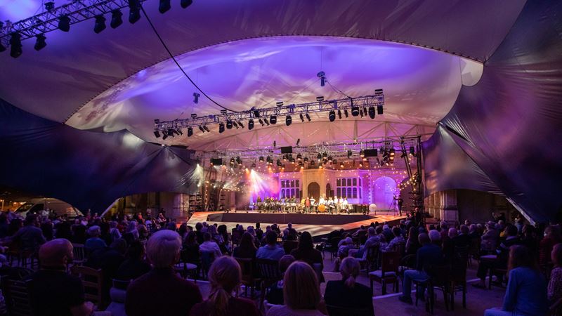Catch a performance at Opera Holland Park. Credit: Ali Wright. Image courtesy of Opera Holland Park. Lights illuminate the stage in front of a big audience at Opera Holland Park, London.