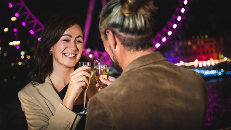 Have a night to remember at the Tattershall Castle and enjoy stunning views of London's New Year's Eve fireworks display. Credit: Golden Tours. Image courtesy of Golden Tours. Two people clinking champagne glasses together in front of the London Eye.