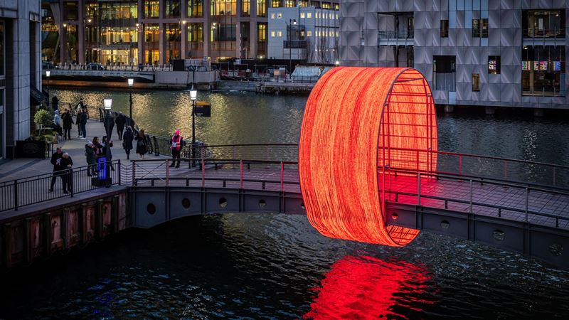 The Clew by Ottotto, a light installation on Cubitt Bridge made from 100 circles of red light. Credit: Canary Wharf Winter Lights. Image courtesy of Canary Wharf Winter Lights. The Clew, a light installation on Cubitt Bridge in Canary Wharf, is made from 100 circles of red light. It was created by Ottotto, a portuguese architectural firm.