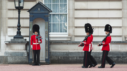 See guards dressed in traditional red tunics and bearskin hats during the Changing of the Guard. Credit: Shutterstock. Image courtesy of Shutterstock.