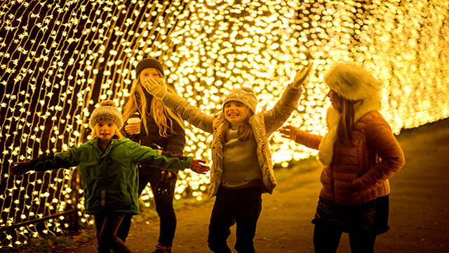 Children run through the cathedral of light tunnel at christmas at kew gardens in london. 