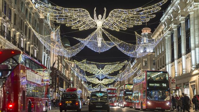 White angel-shaped Christmas lights span the two sides of Regent Street at night, with buses and taxis on both sides of the road.