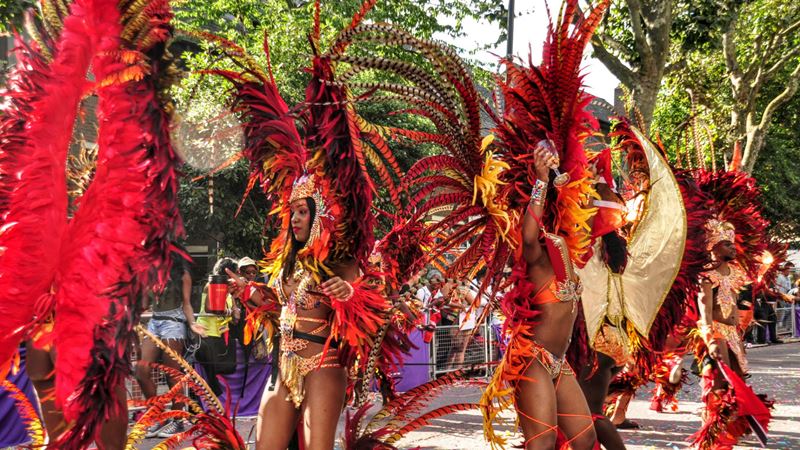 Get ready to dance at the upbeat Notting Hill Carnival in west London. Credit: Carnival Village Trust/Tara Hobson. Image courtesy of Notting Hill Carnival Ltd. A photo of performers enjoying the Notting Hill Carnival 2016, dressed in red costumes.