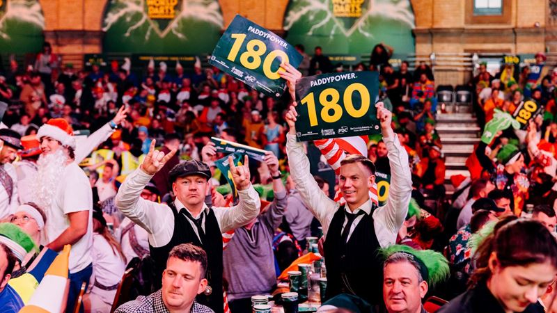 Fans at the alexandra palace darts championship hold up 180 signs.