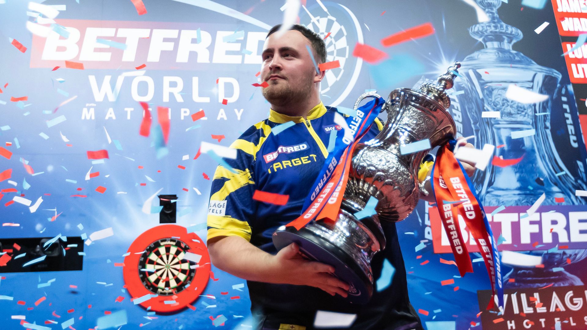 Luke Litter lifts the World Matchplay trophy making him the youngest ever player to complete the Triple Crown of darts. Image courtesy of PDC. Photo Credit: Taylor Lanning Luke Litter lifts the World Matchplay trophy showered in blue and red confetti.