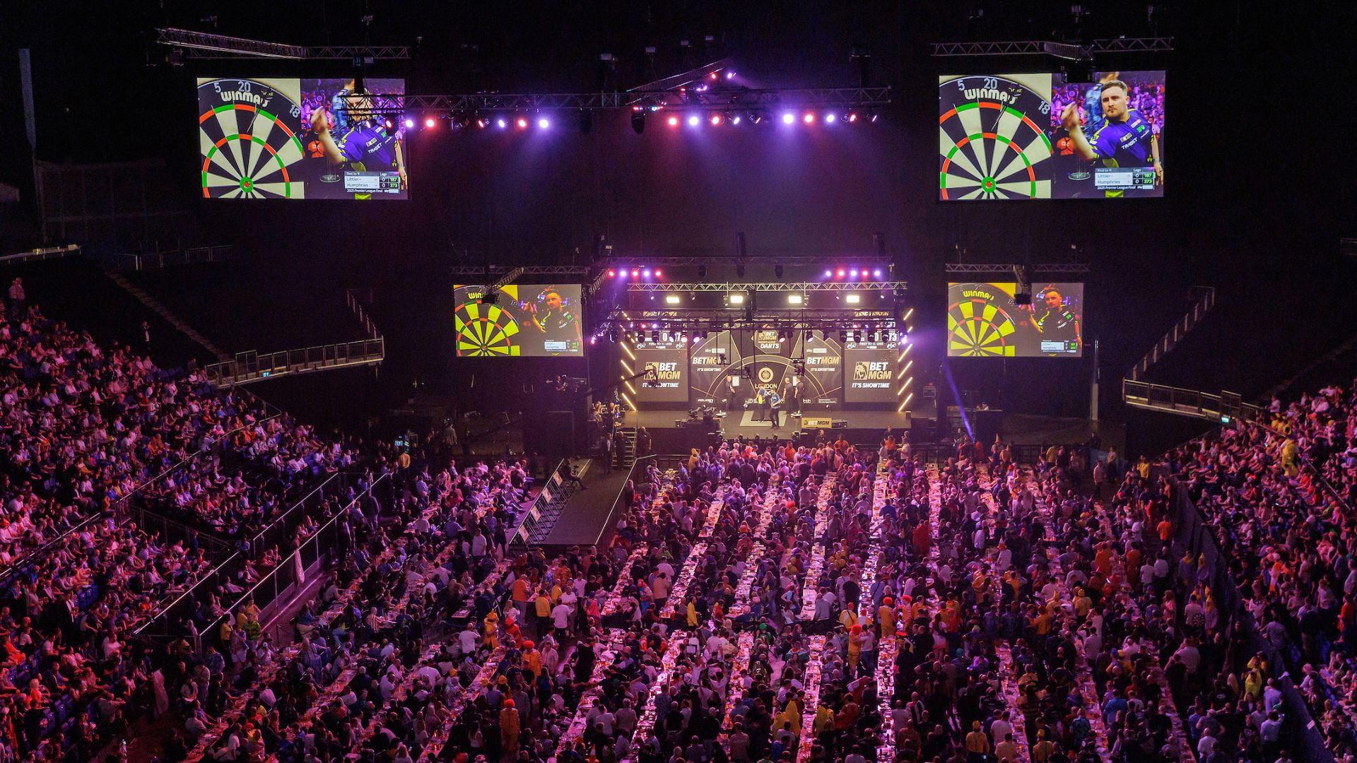 The world's best darts players go head to head at The O2 in London. Image courtesy of PDC. Photo Credit: Simon O'connor Crowds sit in front of the stage at the darts world matchplay final at the O2 London.