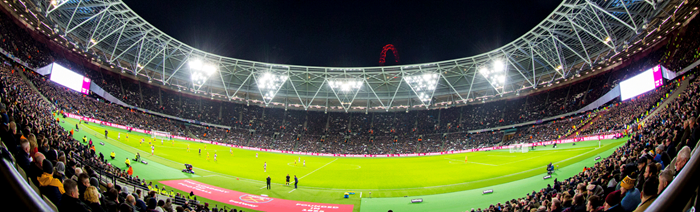 Fans surround the lit up pitch during a game of football at The London Stadium
