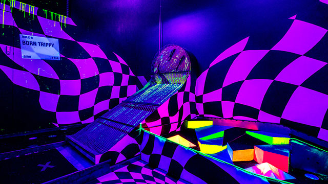 Play crazy golf in a neon jungle at Junkyard Golf Club in Shoreditch © Junkyard Golf Club. Image courtesy of Junkyard Golf Club. A neon purple golf obstacle with multi-coloured light boxes and a wall covered with black and purple checks in the background
