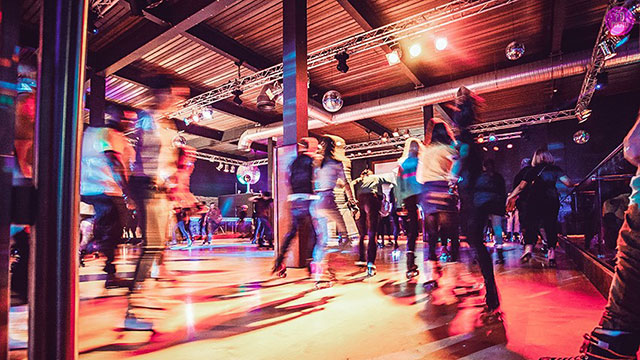 Enjoy a retro-style roller skating disco in London. Image courtesy of Roller Nation. People roller skating around the roller disco rink at Roller Nation.