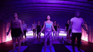 A hotpod yoga class in a dark pod with pink lights