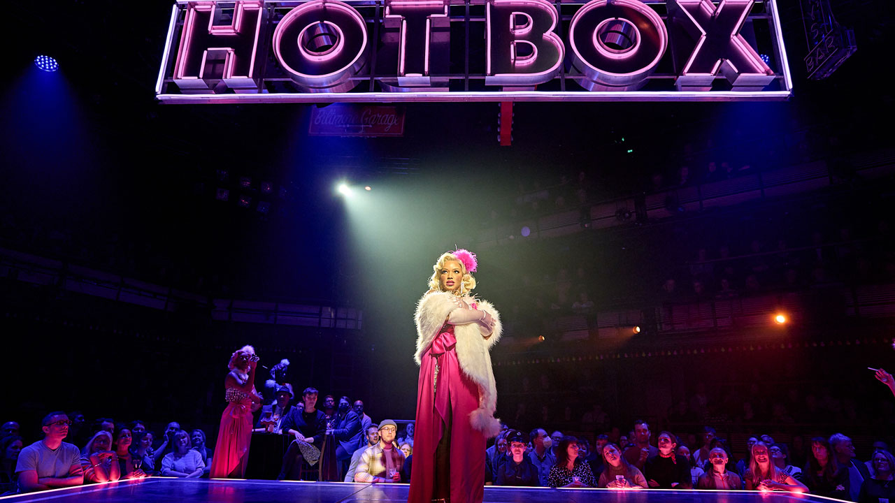 See Marisha Wallace playing Adelaide in the smash hit musical Guys and Dolls at the Bridge Theatre in London. Image courtesy of Premier Entertainement/ photo credit Manuel Harlan. Marisha Wallace plays Adelaide on Guys and DOlls, wearing a pink gown.