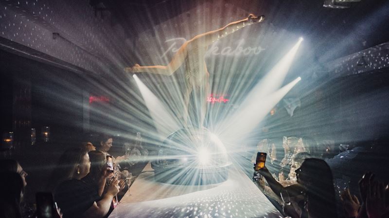 An artist perform some acrobatics on the stage of Circus London with the udience seating on each side of the stage.