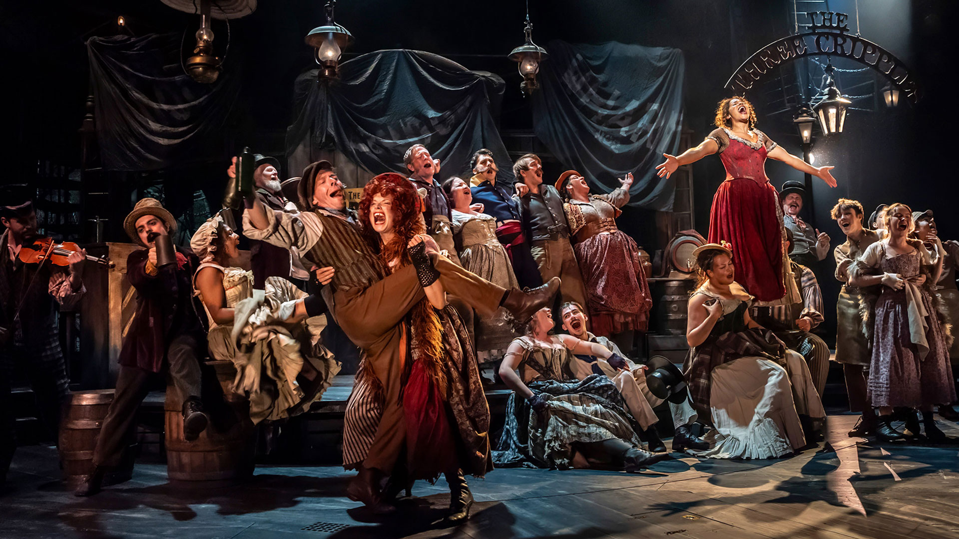 See the Dickens masterpiece Oliver Twist live on stage with the new theatrical production of Oliver! The Musical at the Gielgud Theatre. Image courtesy of Storyhouse PR/ Photo credit: Johan Persson. Women and men dressed in period costumes from the Victorian era dance and sing together in a party-like setting in the new production of Oliver! The Musical.