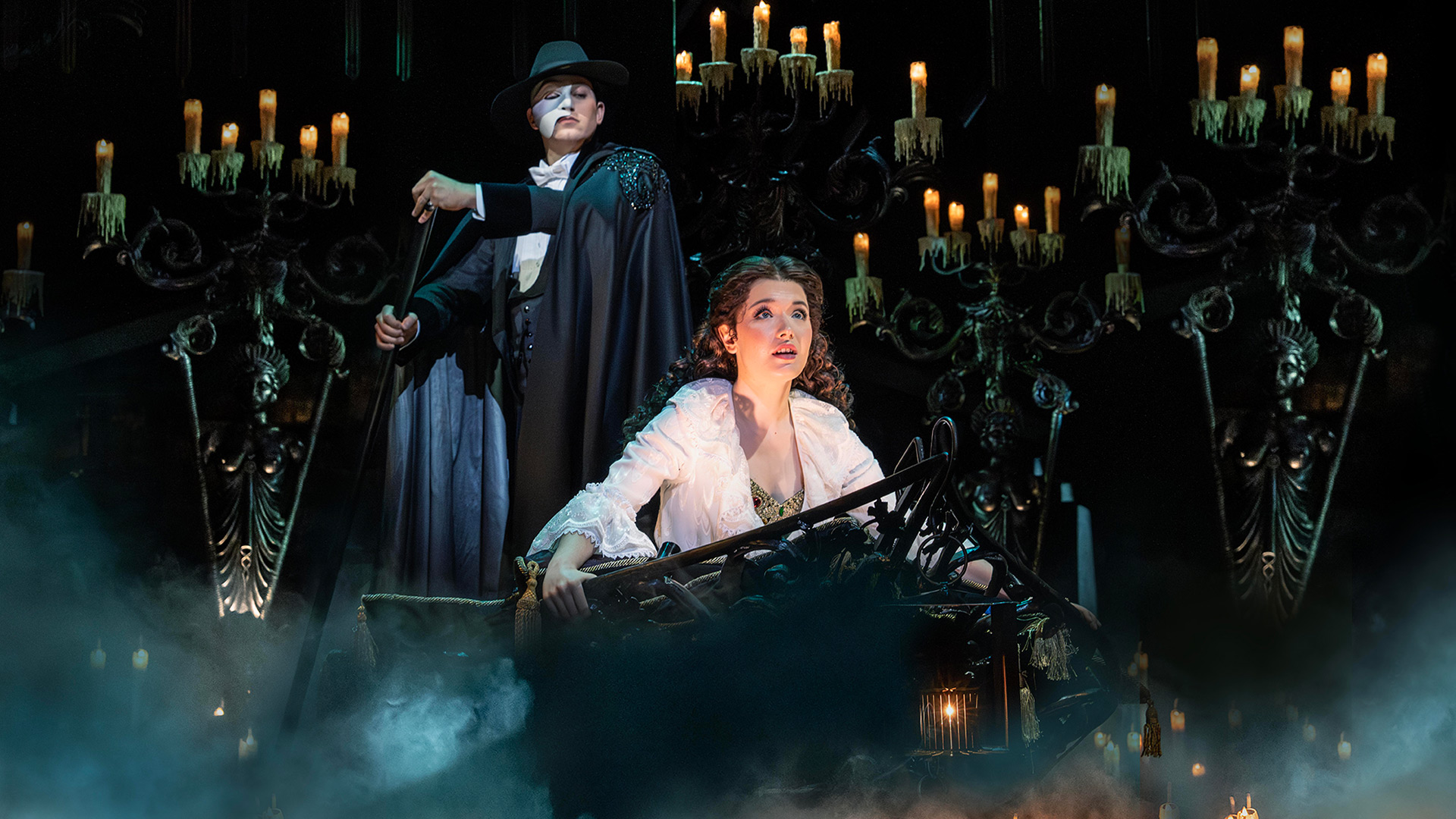 See the majestic Andrew Lloyd Webber's award-winning musical, The Phantom of the Opera at Her Majesty's Theatre. Image courtesy of Raw PR/ photo credit: Johan Persson The Phantom of the Opera, wearing a mask hiding half of his face, stands above Christine, a young opera singer.
