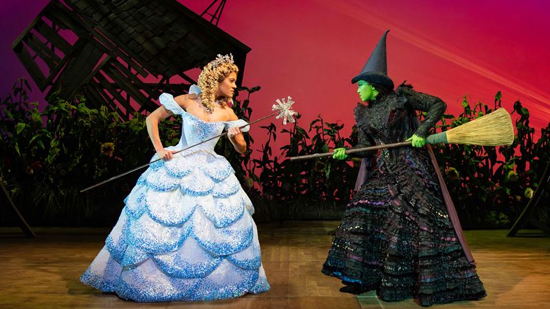 Follow the story of Glinda the Good and Elphaba the Wicked Witch of the West with the mesmerising Wicked the Musical. Credit: Matt Crockett. Image courtesy of WLP 2024L. Glinda The Good is wearing a light blue gown and is fighting of Elphaba the Wicked Witch who is branding her broom.