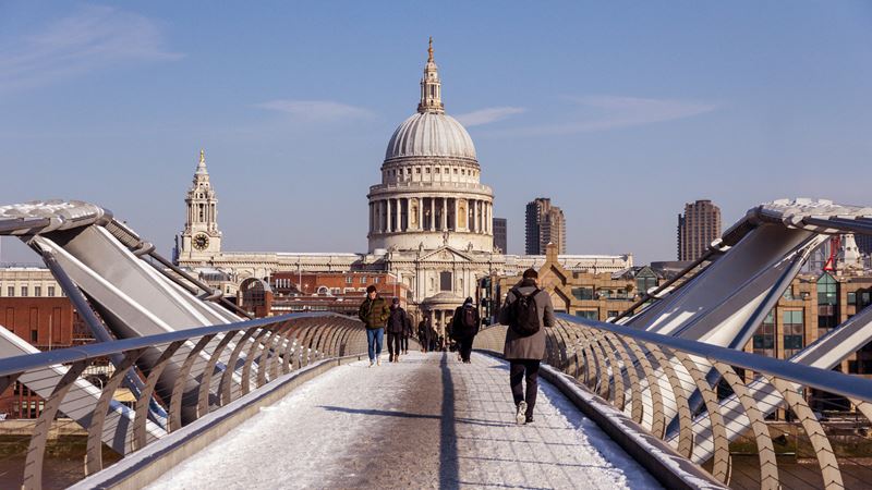 St Paul's Cathedral is just one of many locations used in the top films. Credit: Shutterstock. Image courtesy of Shutterstock. People walking across the London Millennium Bridge in the snow against the backdrop of St Paul's Cathedral.