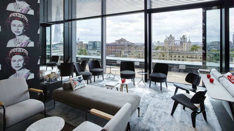 Book a room at citizenM Tower of London for breathtaking views of the iconic landmark. Credit: citizenM. Image courtesy of citizenM. A photo of a communal area at Citizen M Tower of London with comfortable chairs, sofas and pop art imagery on the walls with floor-to-ceiling windows boasting views of the London skyline including The Tower of London and The Shard