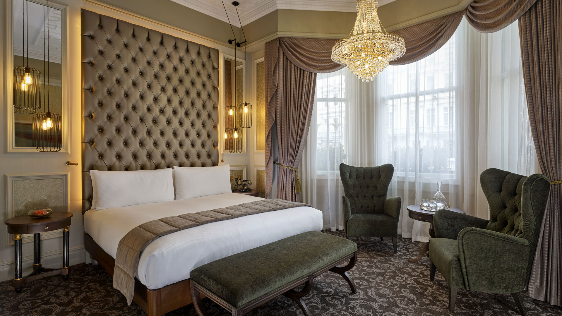 Indulge an elegant stay at 100 Queen's Gate Hotel London, Curio Collection by Hilton. Image courtesy of Hilton. Bedroom with plush details and chandelier at 100 Queen's Gate Hotel London.