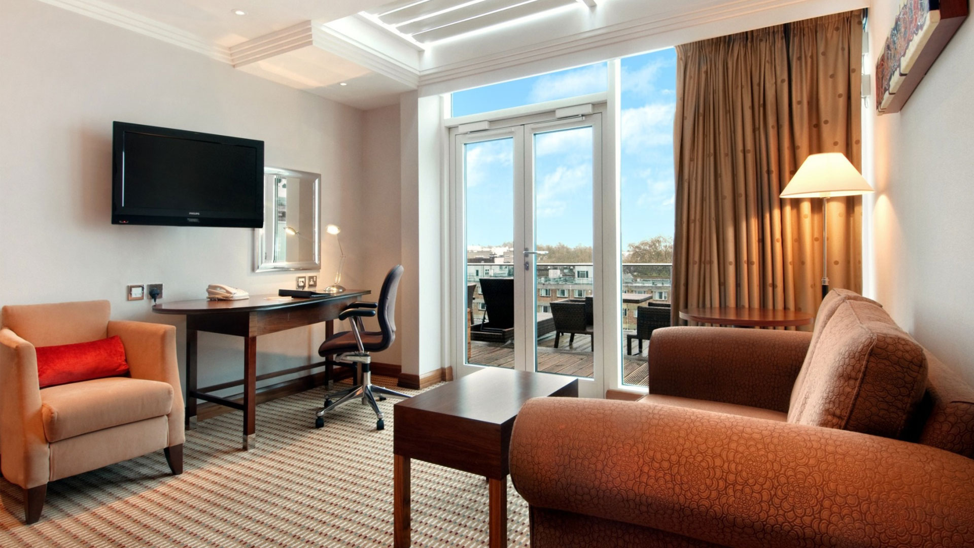 Relax in the Family Terrace Suite at Hilton London Paddington. Image courtesy of Hilton. Lounge of Family Terrace Suite with view of outdoor balcony at Hilton London Paddington.