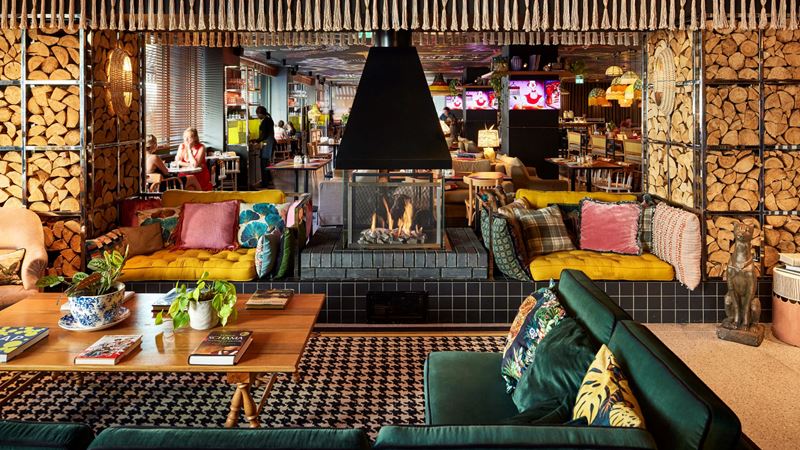 Relax in the eccentric surroundings of The Mama Shelter hotel lounge. Credit: Francis Amiand. Image courtesy of Mama Shelter. The colourful lounge at Mama Shelter featuring a log fireplace, quirky carpets and teal velvet sofas