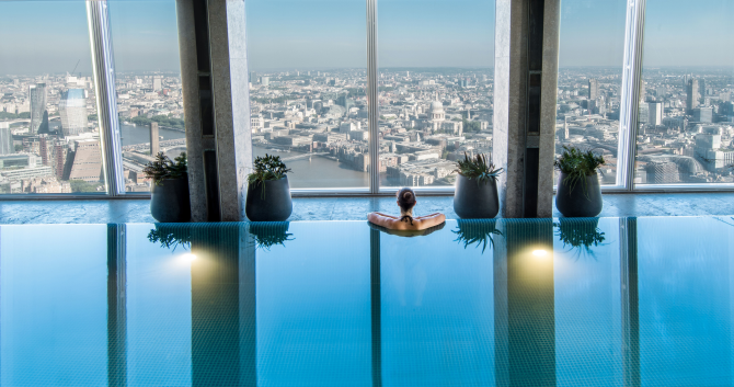 Watch the world go by from the pool at Shangri-La The Shard, London. Credit: Shangri-La The Shard. Image courtesy of Shangri-La The Shard. Woman looks out over London skyline from Shangri-La The Shard Sky Pool