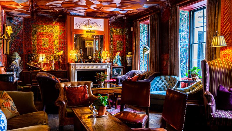 Warm up next to the fireplace at The Zetter Clerkenwell hotel bar. Credit: The Zetter Clerkenwell. Image courtesy of The PC Agency. Communal area at Zetter Townhouse Clerkenwell with red patterned wallpaper, velvet sofas and wooden tables